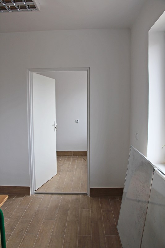 Obrazek przedstawia zdjęcie wyjścia z pokoju - otwarte białe drzwi