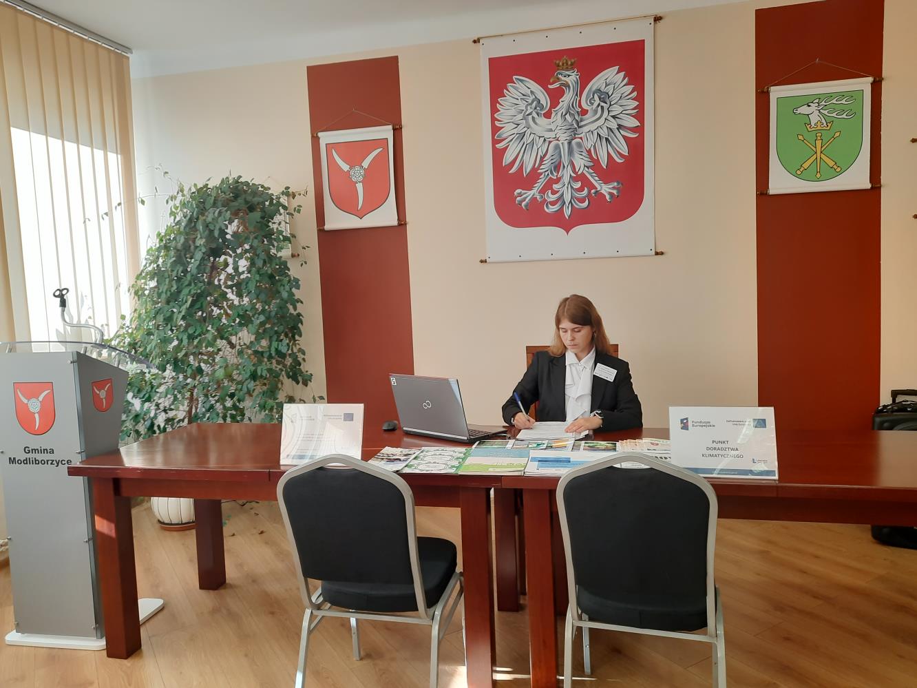 Doradca klimatyczny wraz z materiałami projektowymi na stanowisku pracy w sali narad podczas realizacji Mobilnego Punktu Doradztwa Klimatycznego w Urzędzie Miejskim w Modliborzycach w dniu 6 listopad 2024