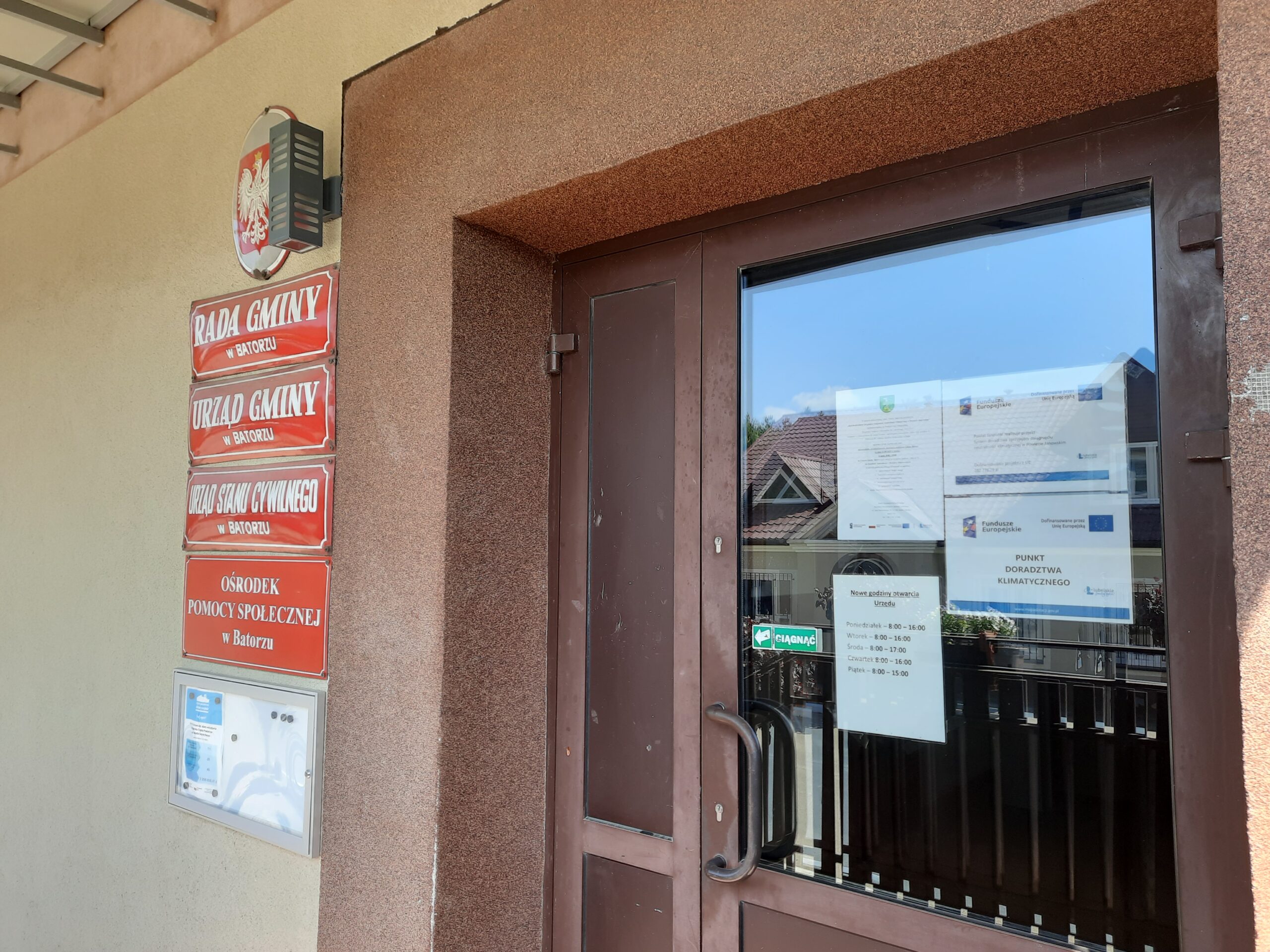 Plakat - Powiat Janowski realizuje projekt: System doradztwa sprzyjający osiągnieciu neutralności klimatycznej w Powiecie Janowskim wraz plakatem Doradztwa Klimatycznego oraz zaproszeniem na bezpłatne konsultacje wywieszony na drzwiach wejściowych budynku Urzędu Gminy Batorz